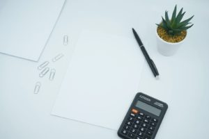 person holding pencil and stick note beside table