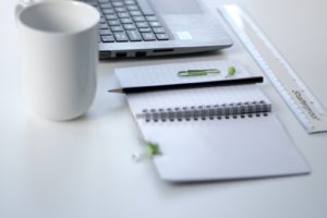 person holding pencil and stick note beside table